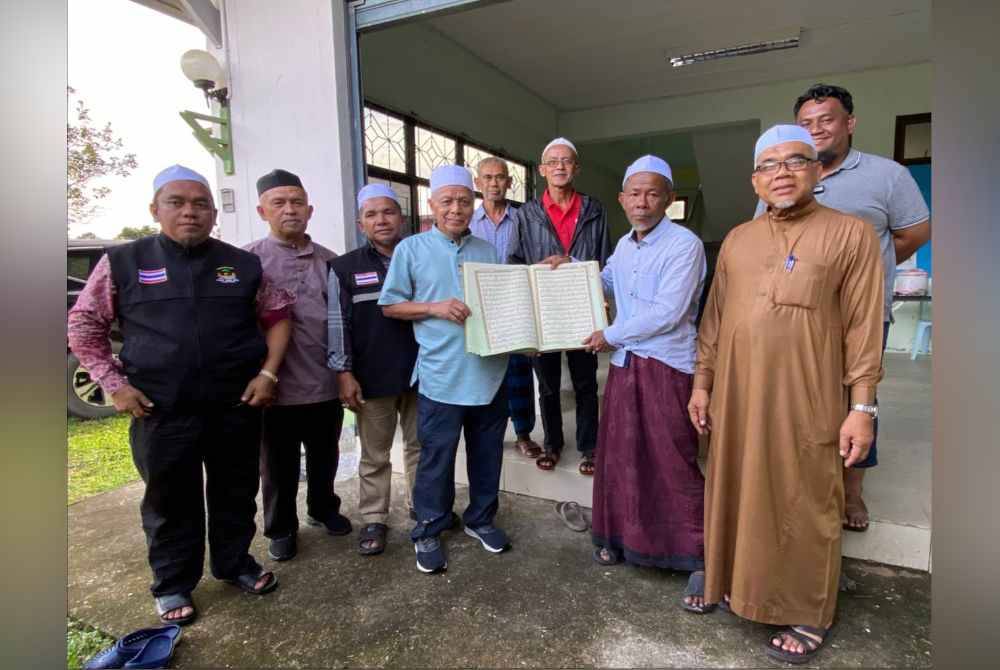 Muhammad Nasir (empat dari kiri) menyampaikan sumbangan al-Quran kepada wakil-wakil masjid di Daerah Rueso, Narathiwat.