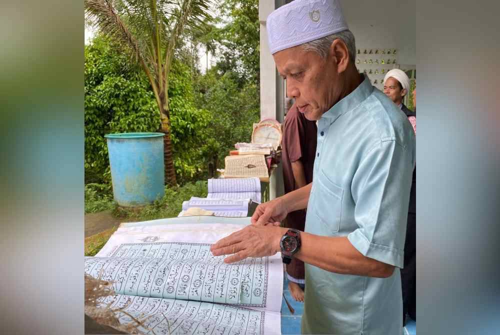 
Muhammad Nasir memeriksa naskah al-Quran yang rosak akibat ditenggelami banjir.