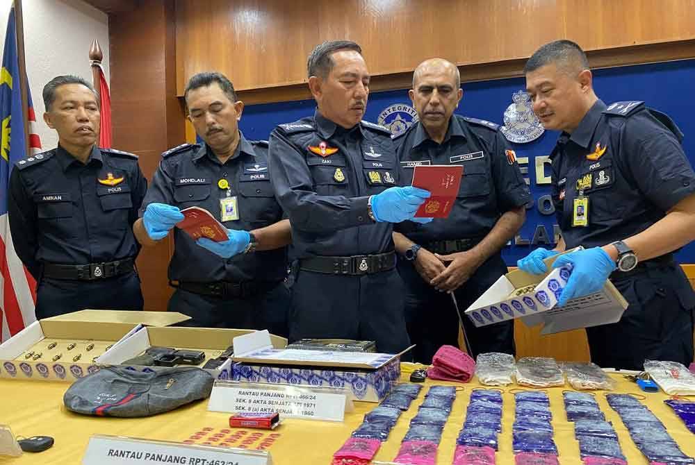 Muhamad Zaki (tengah) menunjukkan pasport milik pasangan suami isteri terbabit yang turut dirampas.