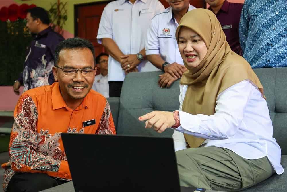 Fadhlina (kanan) bersama Pengetua SMK Seri Nibong, Zulkipli Saleh (kiri) berbual dengan pelajar sekolah itu menerusi Pengajaran dan Pembelajaran di Rumah (PdPR) ketika melakukan lawatan kerja berikutan gangguan bekalan air. Foto Bernama