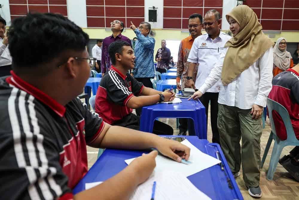 Fadhlina berbual dengan calon peperiksaan SPM ketika melakukan lawatan kerja berikutan gangguan bekalan air di SMK Seri Nibong. Foto Bernama