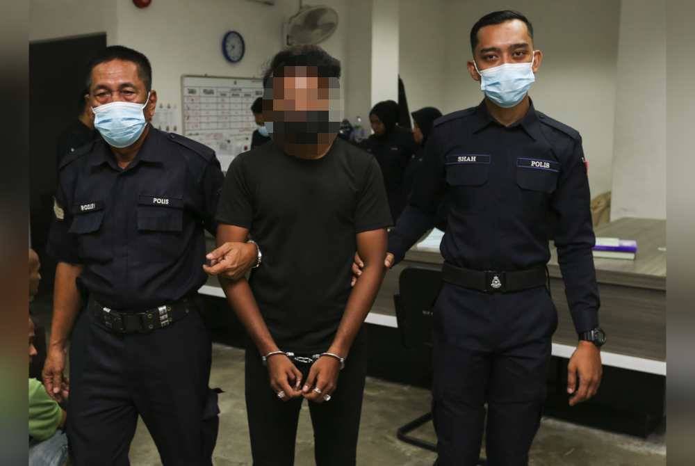 Tertuduh (tengah) hadir ke mahkamah untuk mendengar pertuduhan terhadapnya.