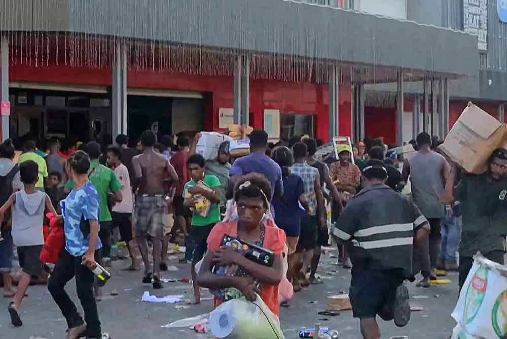 Orang ramai memecah masuk kedai dan mencuri barangan semasa rusuhan berlaku di Port Moresby. Foto AFP