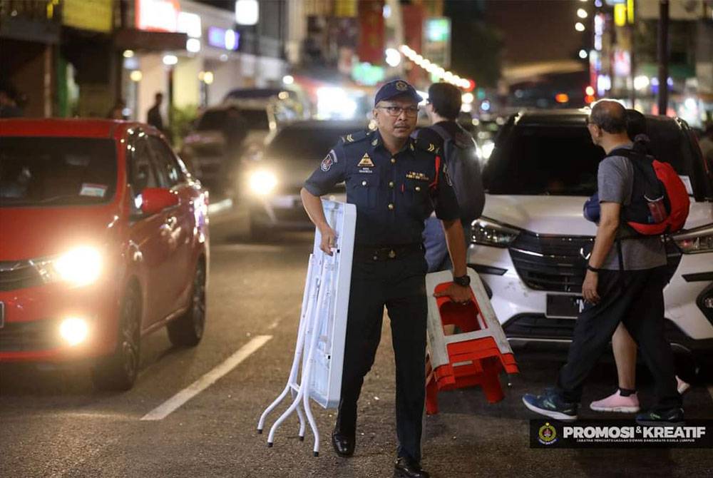 Seorang anggota DBKL mengangkat meja yang disita.