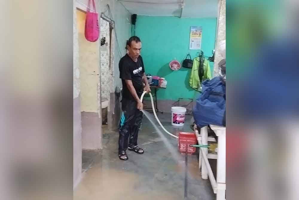 Abu Zarin membersihkan rumahnya yang dipenuhi lumpur akibat banjiir.