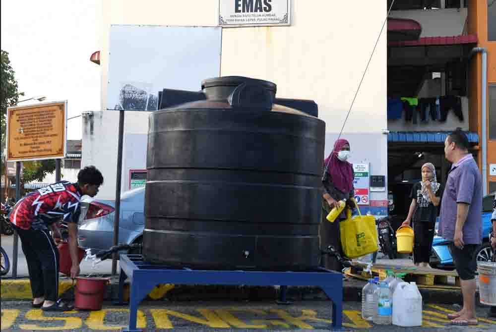 Penduduk flat Taman Emas Batu Maung mendapat air dari tangki air yang disediakan. Foto Bernama