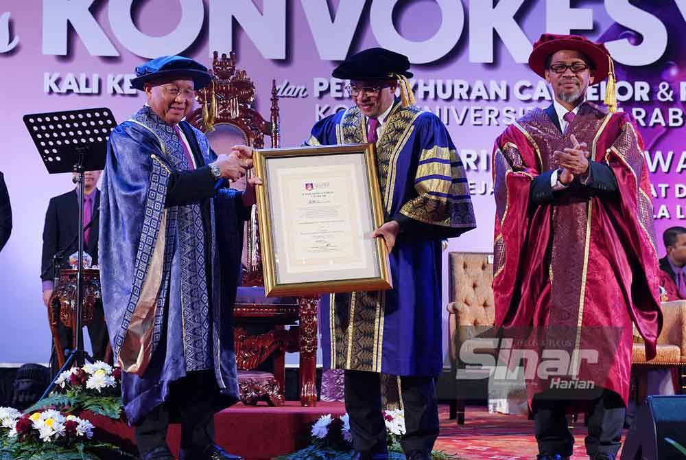 Mohd Daud (tengah) menyampaikan watikah pelantikan Canselor kepada Tan Sri Azman Hashim pada Majlis Konvokesyen UCMI kali ke-14 di Pusat Dagangan Dunia Kuala Lumpur (WTCKL) pada Sabtu. FOTO SINAR HARIAN/MOHD HALIM