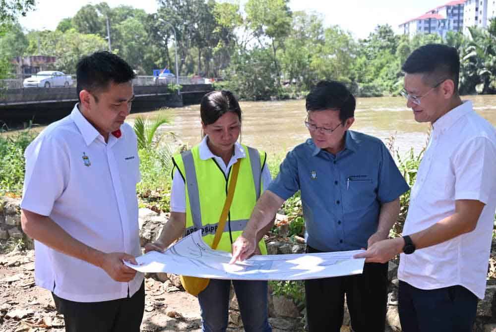 Kon Yeow (dua dari kanan) melihat peta pembinaan paip lencongan yang merentasi atas Sungai Perai.