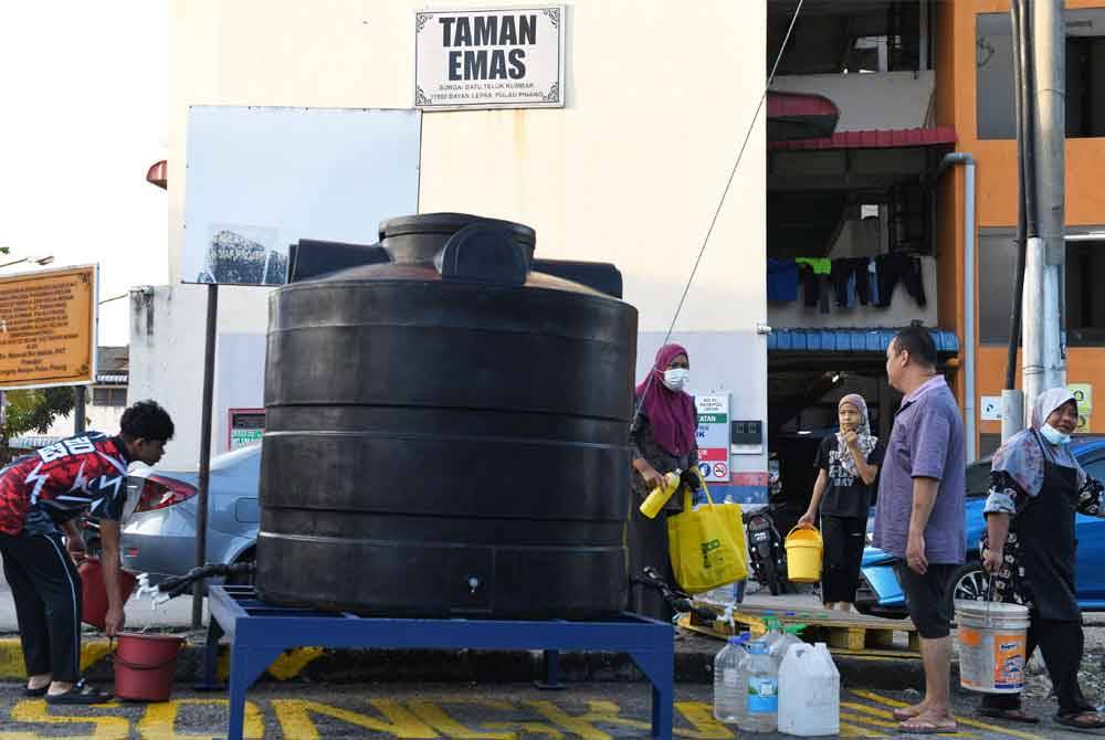 Penduduk flat Taman Emas Batu Maung mendapat air dari tangki air yang disediakan. Foto Bernama