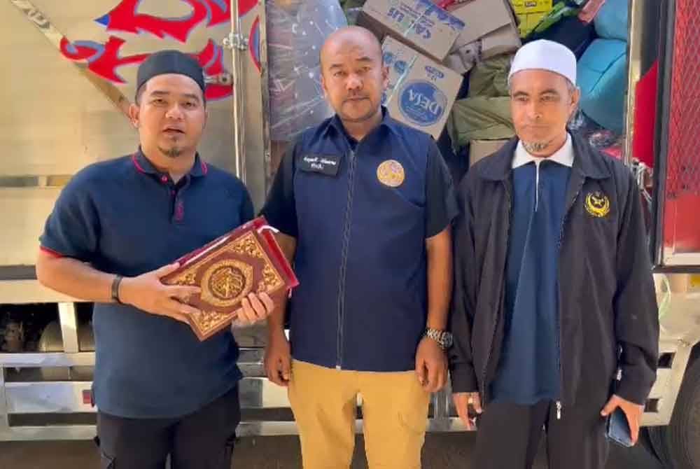 Mohamad Afandi (kiri) menyerahkan al-Quran kepada pihak di selatan Thailand.