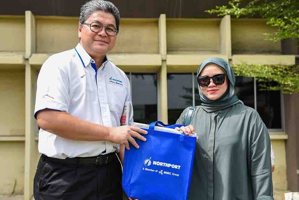 Azman Shah (kiri) menyampaikan cenderahati kepada Farah di pekarangan bangunan Northpole pada Jumaat.