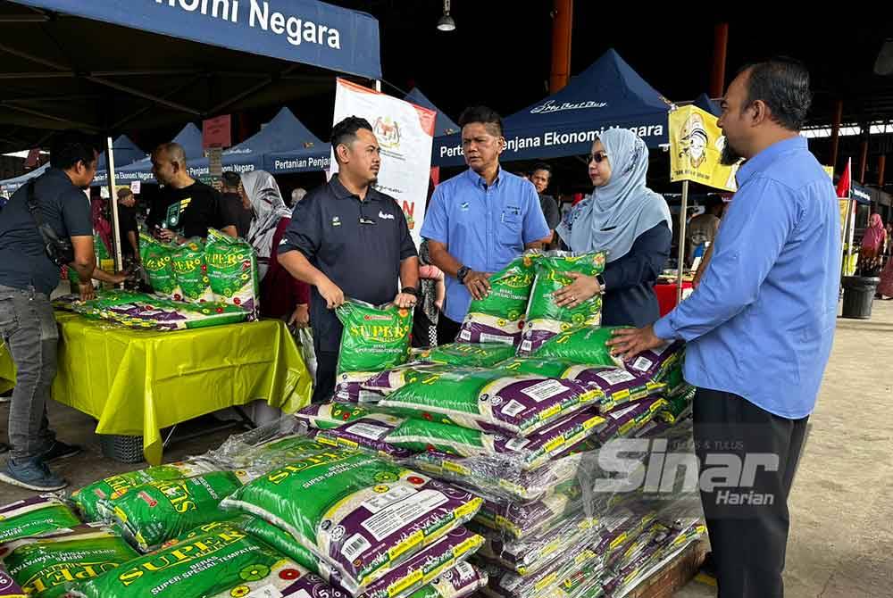 Abd Rahman (tiga dari kanan) dan Wan Faizatul Aniza (dua dari kanan) melihat beras yang dijual di Program Jualan Agro Madani pada Isnin.
