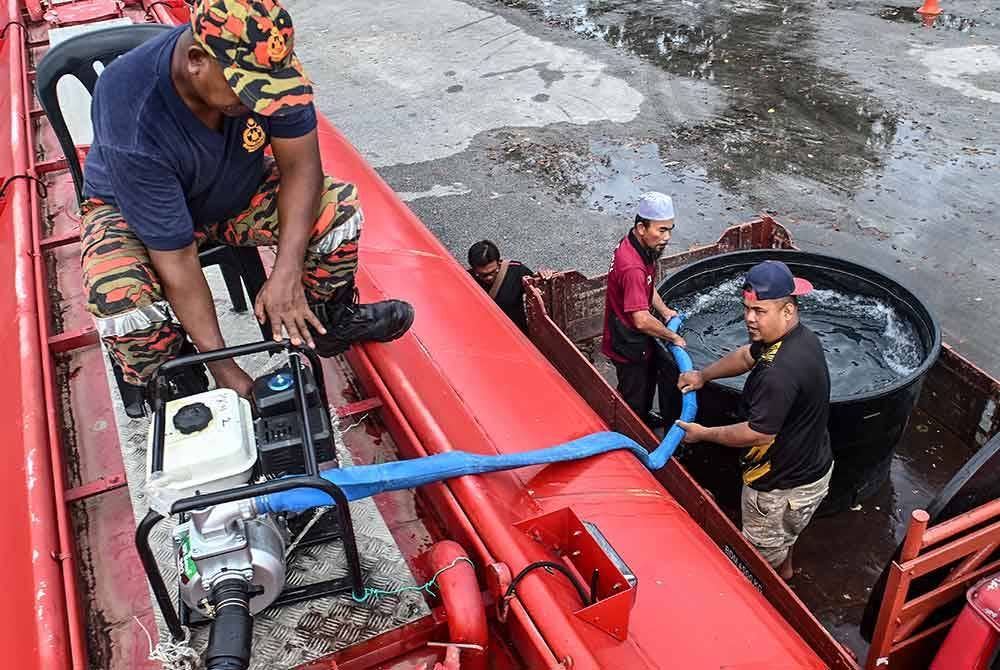 Anggota bomba membantu mengisi air ke dalam sebuah tangki untuk kegunaan penduduk yang mengalami gangguan bekalan air di Dataran Limbungan, Dewan Undangan Negeri (DUN) Kota Putera, Besut, baru-baru ini. - Foto Bernama