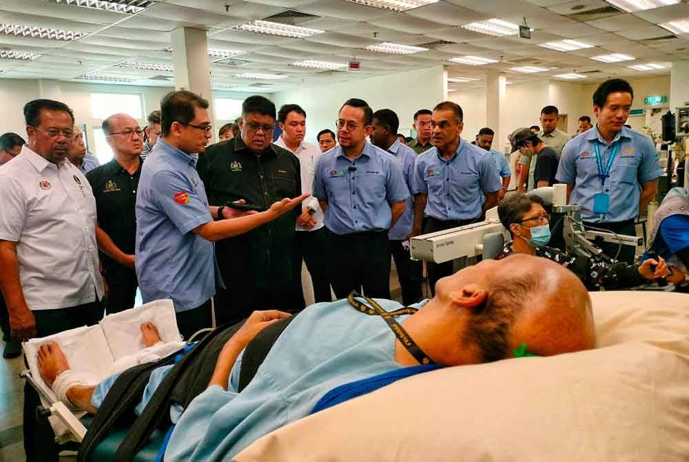 Steven Sim (tengah) meninjau seorang pesakit terlantar sakit yang turut mendapatkan rawatan di Pusat Rehabilitasi PERKESO.