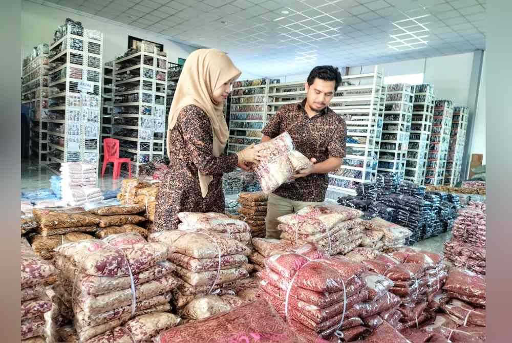 Mohd Hidayat dan Siti Murni sedang menyusun stok baju yang baru tiba di gudang mereka di Wisma Dhia Cotton.