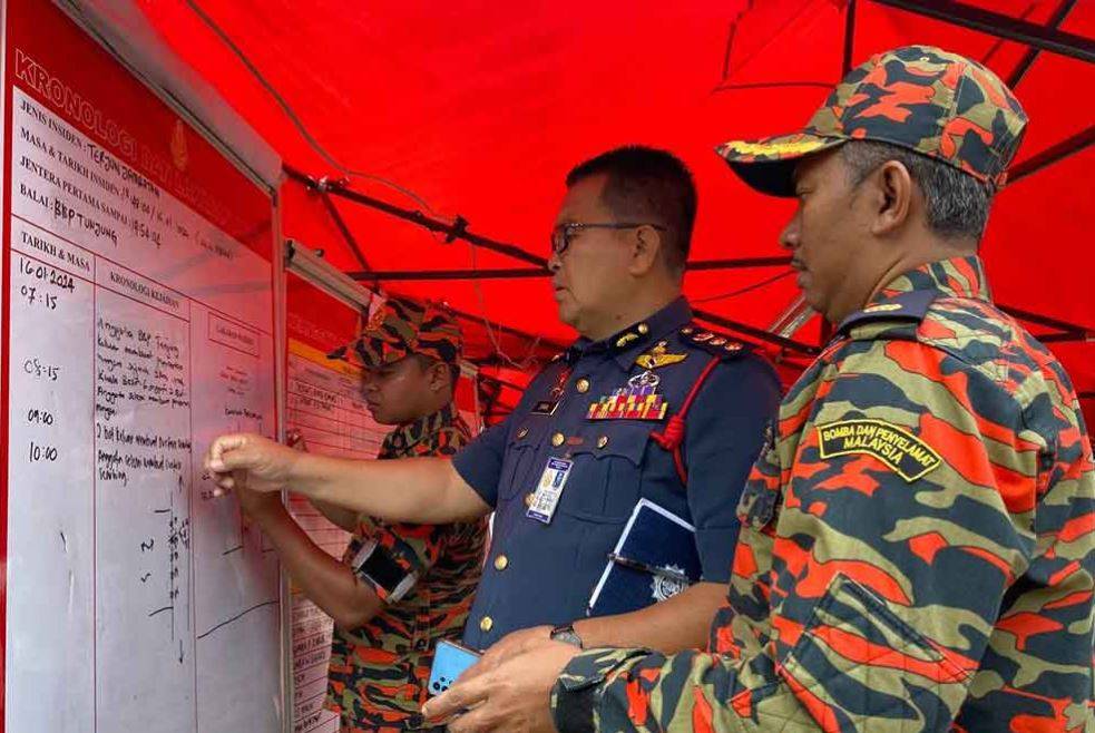 Zainal (dua, kanan) melihat gerak kerja SAR di lokasi kejadian, di Tendong, Pasir Mas.