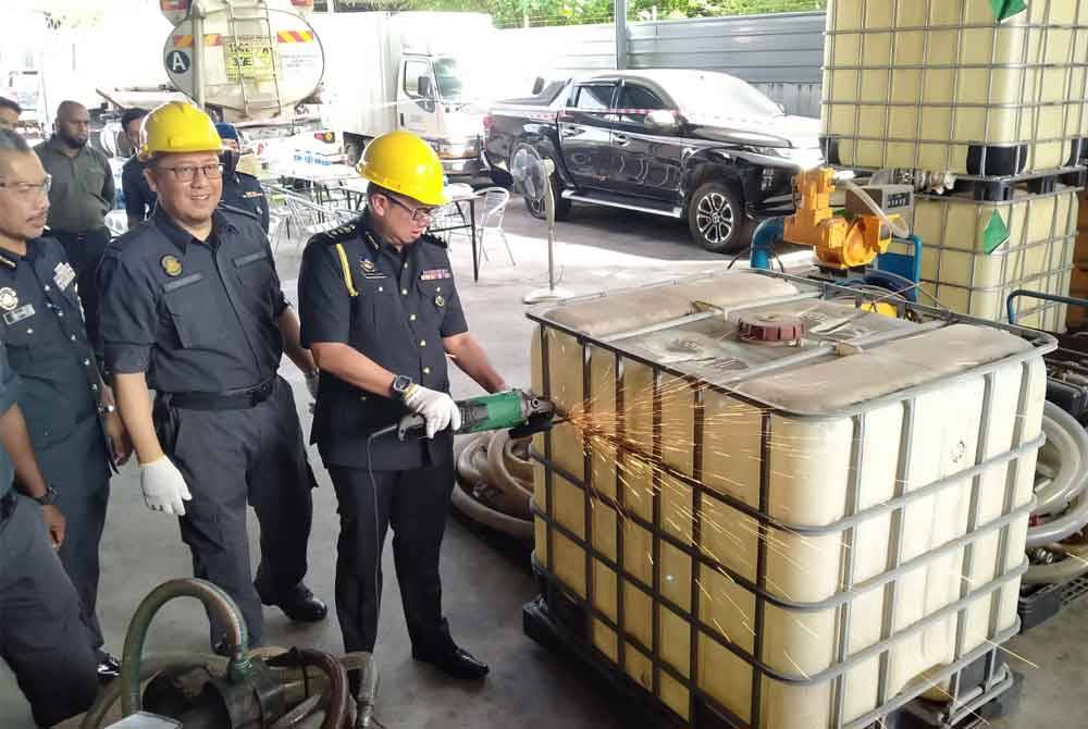 Kamalludin (kanan) memotong besi tangki simpanan minyak diesel sebagai gimik sempena Program Pelupusan Ekshibit Perdana di Stor Penyimpanan Ekshibit KPDN Perak, Kawasan Perusahaan IGB di sini pada Selasa.