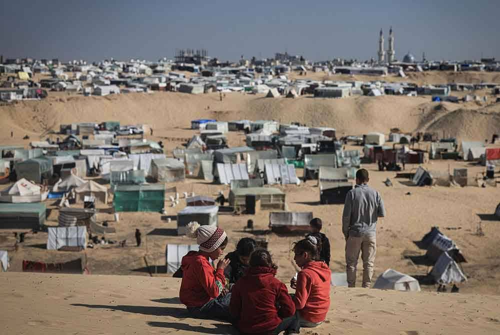 Kanak-kanak Palestin bermain di atas bukit pasir, menghadap kem sementara di sempadan selatan Semenanjung Gaza, Palestin dan Mesir. Foto AFP