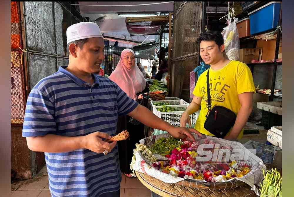 Mohd Asrul Faizal (kiri) membeli beluru dan bunga-bungaan untuk digunakan sebagai mandian tradisional. Foto SINAR HARIAN