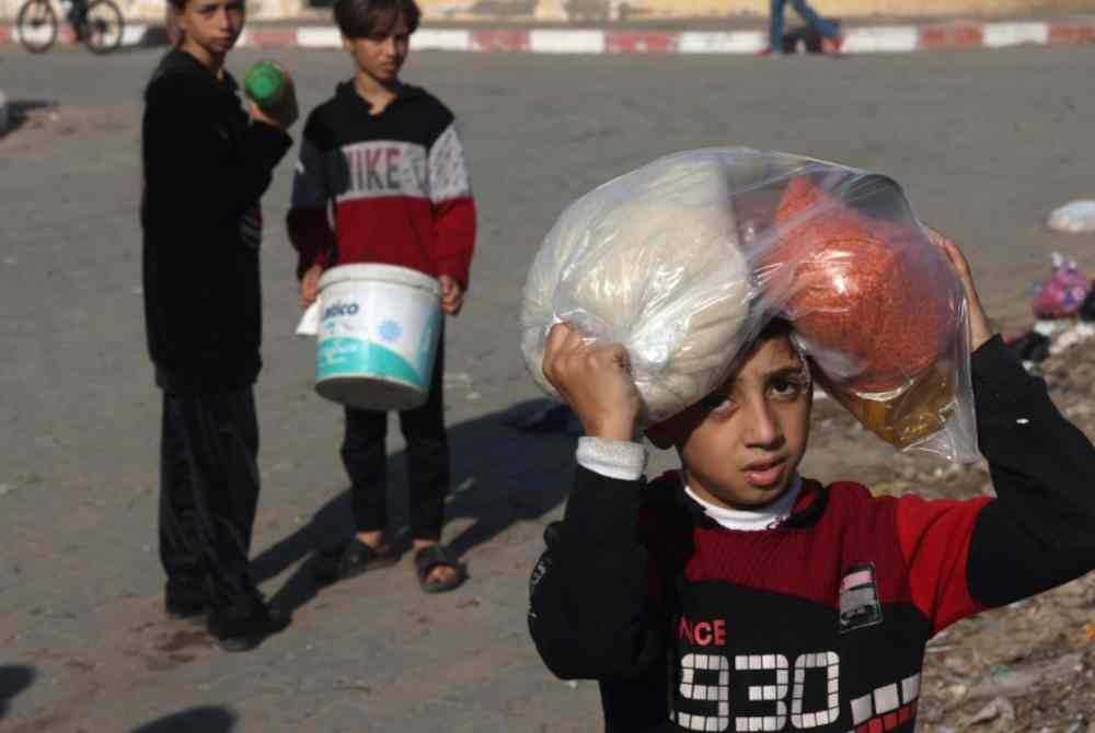 Beberapa kanak-kanak Palestin mengambil makanan yang diberikan secara percuma oleh badan amal.