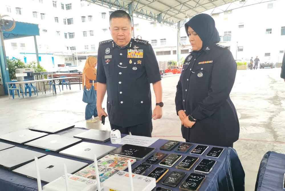 Kok Chin (kiri) melihat barangan yang dirampas pada sidang akhbar di IPK Pulau Pinang.