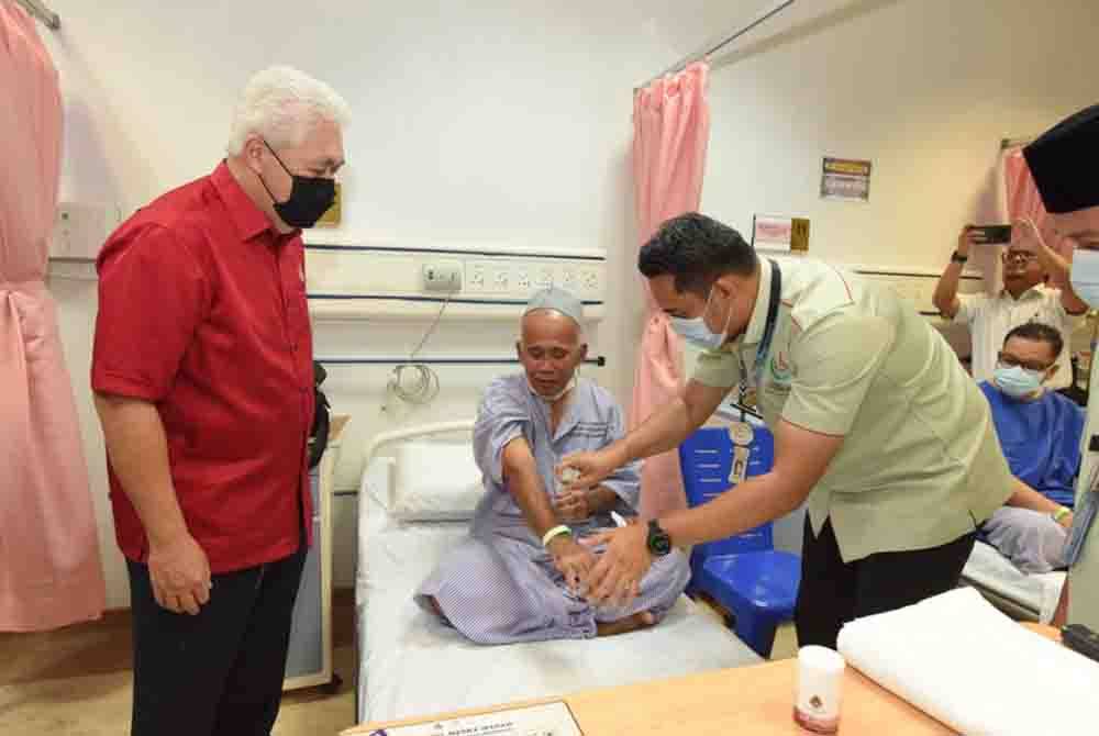 Tengku Mohamad Rizam (kiri) menyaksikan cara-cara berwuduk bagi pesakit. Foto MAIK
