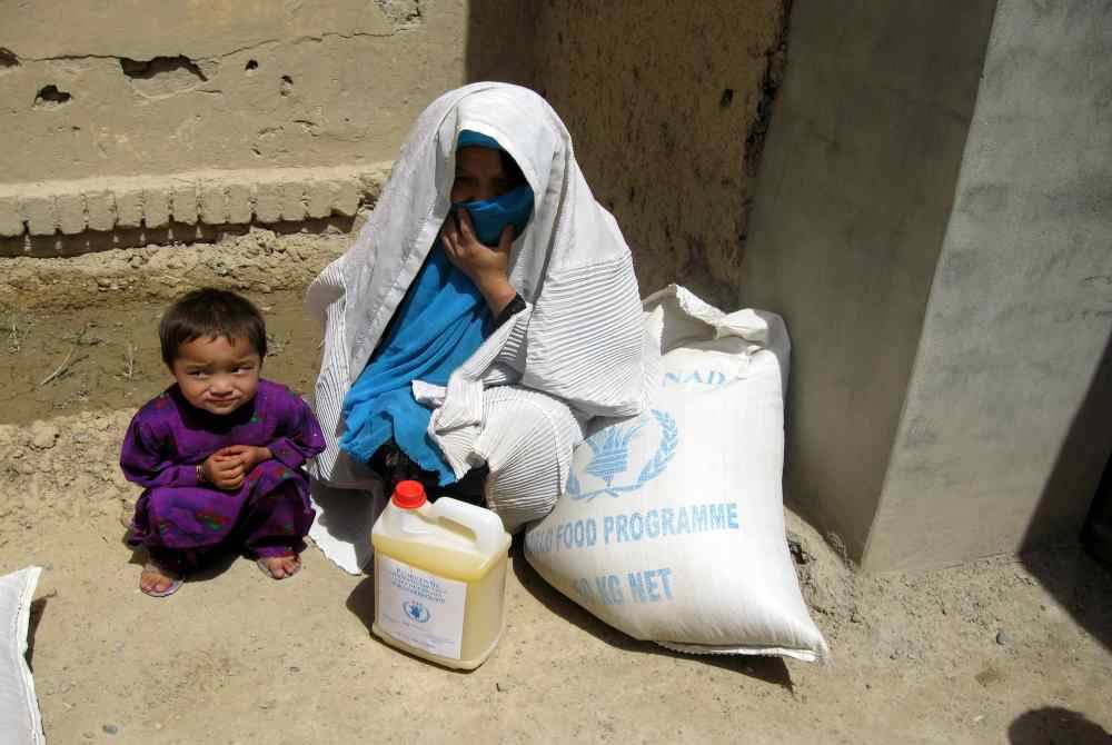 Seorang wanita dan anaknya yang selesai menerima bantuan makanan. Foto Agensi
