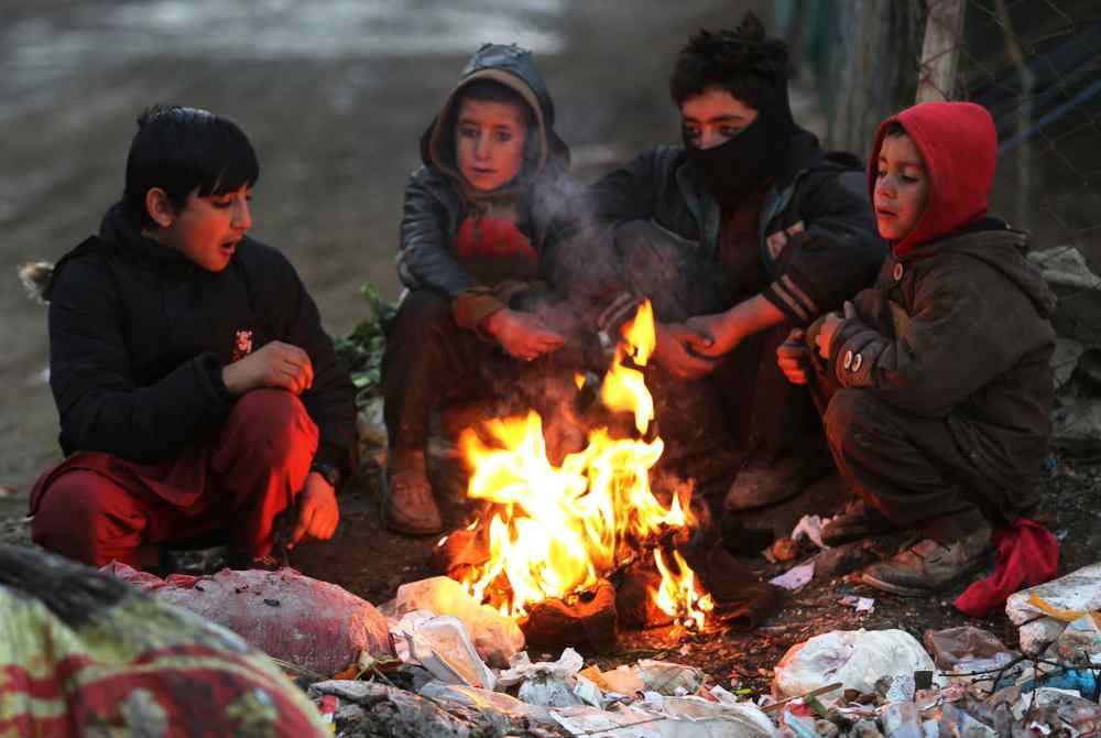 Kanak-kanak Afghanistan memanaskan badan di tepi jalan raya ketika cuaca sejuk melanda Kabul. Foto AFP