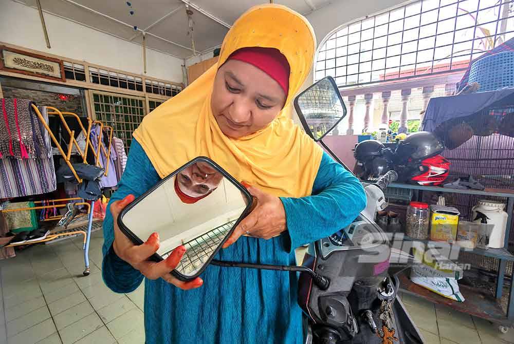 Siti Aminah memasang cermin sisi lori satu tan pada motosikalnya demi keselesaannya di jalan raya.