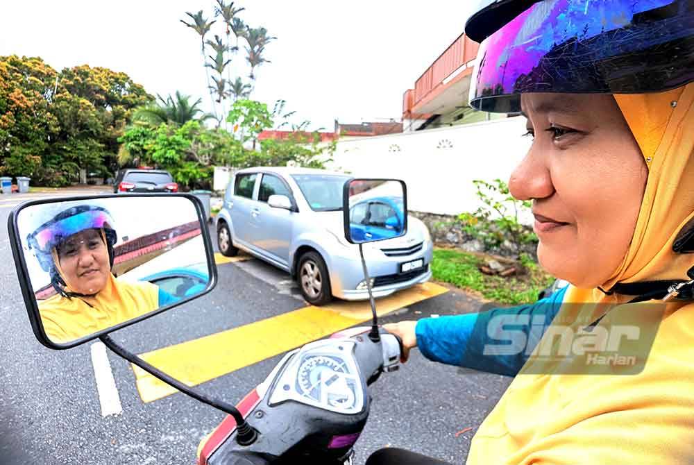 Siti Aminah melihat pada cermin motosikalnya yang bersaiz besar.
