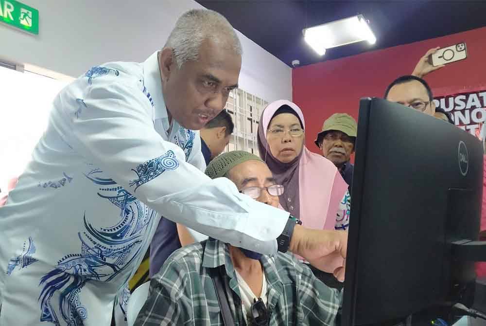 Khairudin (kiri) meninjau pendaftaran PADU di PEDi Bota pada Khamis.