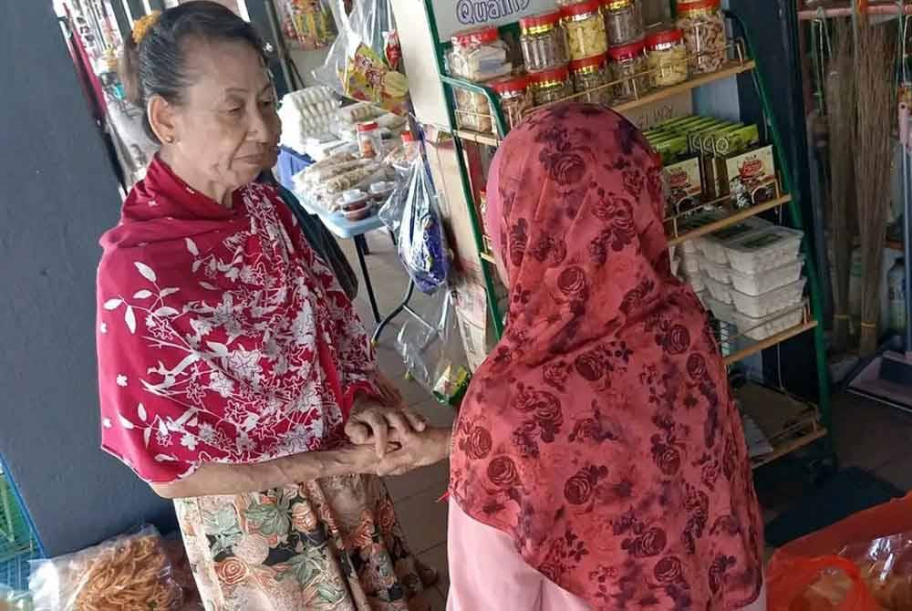 Suson (kiri) berbual bersama salah seorang pelanggan yang singgah di gerainya yang menjual kerepek di Pasar Awam Sungai Besar di sini.