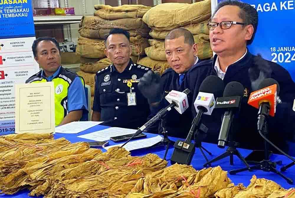 Zailani (kanan) menunjukkan sebahagian daripada tembakau yang dirampas.