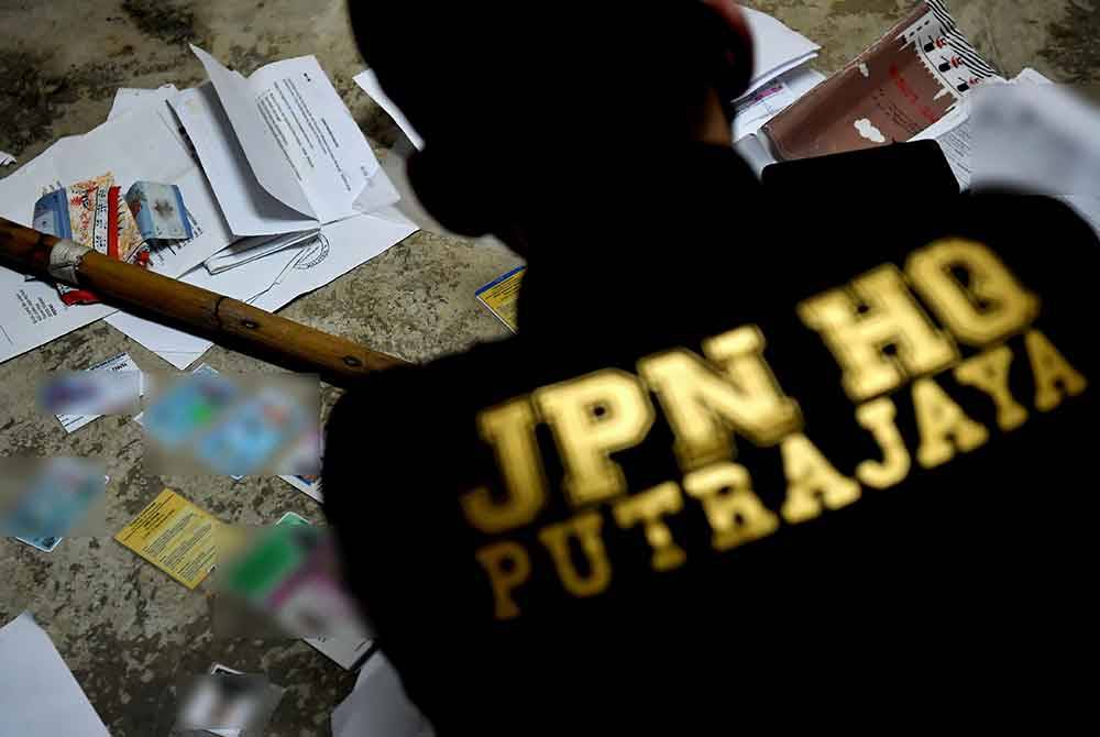 Pegawai dan anggota JPN Putrajaya memeriksa dokumen peribadi seorang individu yang ditahan dalam satu operasi yang dijalankan di sekitar Pulau Indah hari ini. Foto Bernama