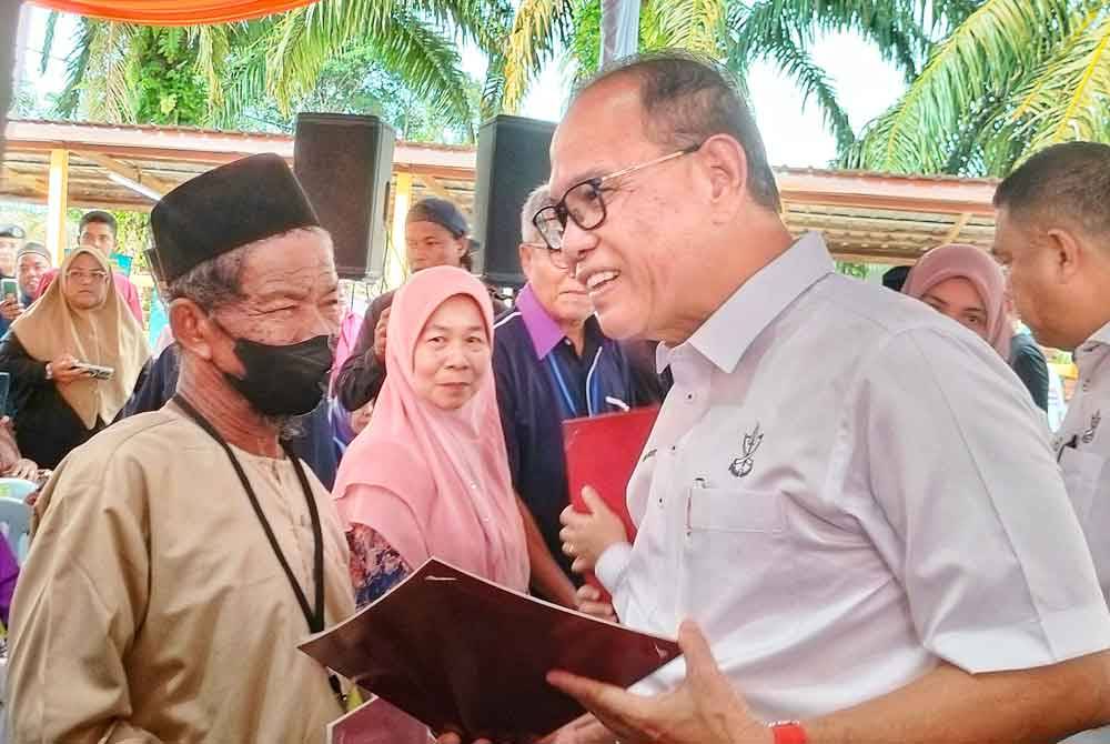 Wan Rosdy (Kanan) bertanyakan sesuatu kepada peneroka yang jelas ceria menerima suratan hak milik masing-masing.