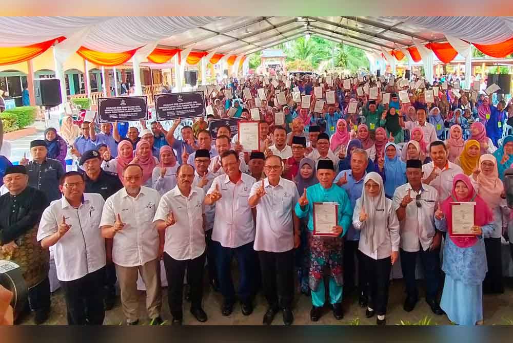 Sebahagian penerima suratan hak milik dan STR ceria bergambar kenangan bersama Wan Rosdy pada Jumaat.