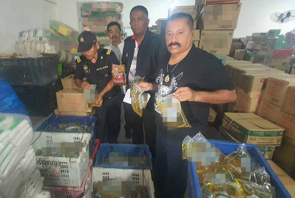 Jegan (dua dari kanan) bersama pegawai penguat kuasa KPDN menunjukkan minyak masak yang dirampas dalam serbuan di sebuah pasar raya di Sungai Jawi pada Jumaat.