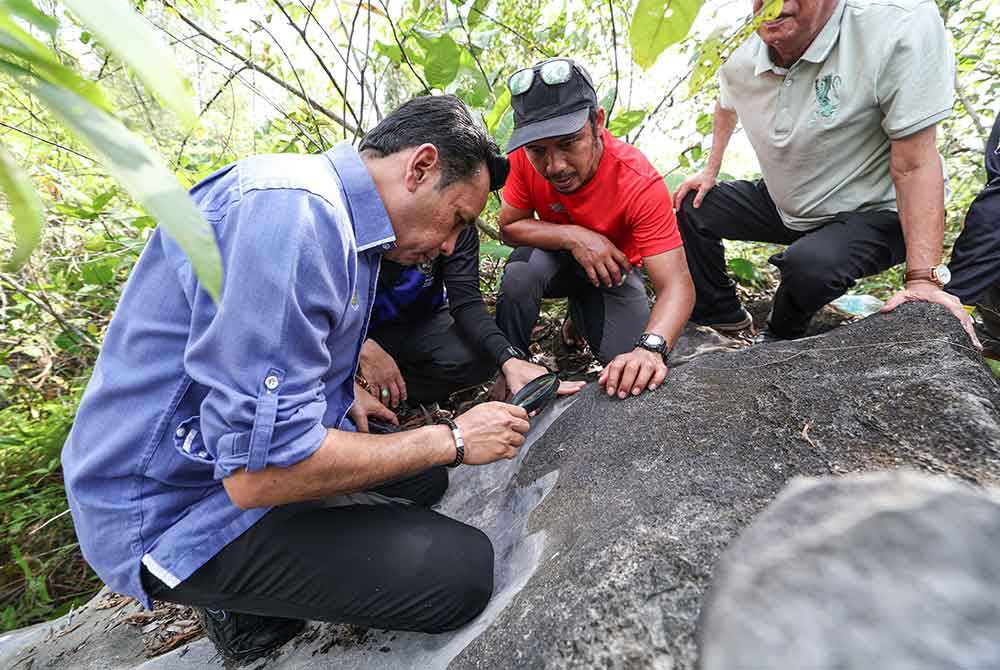 Pengerusi Jawatankuasa Komunikasi, Multimedia dan NGO Perak, Mohd Azlan Helmi Helmi (kiri) meneliti fosil yang melekat pada batu-batuan ketika mengadakan lawatan ke sebuah kawasan berdekatan Kampung Changkat Tualang semalam. Foto Bernama