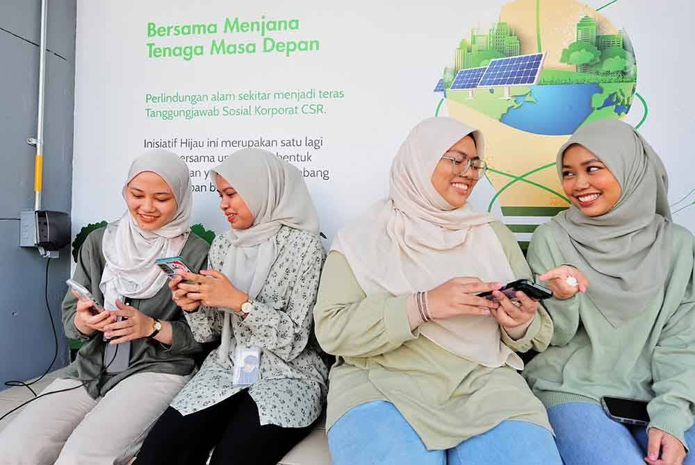 Pelajar mencuba pengecasan gajet di salah sebuah perhentian bas berkuasa solar di UiTM Shah Alam.