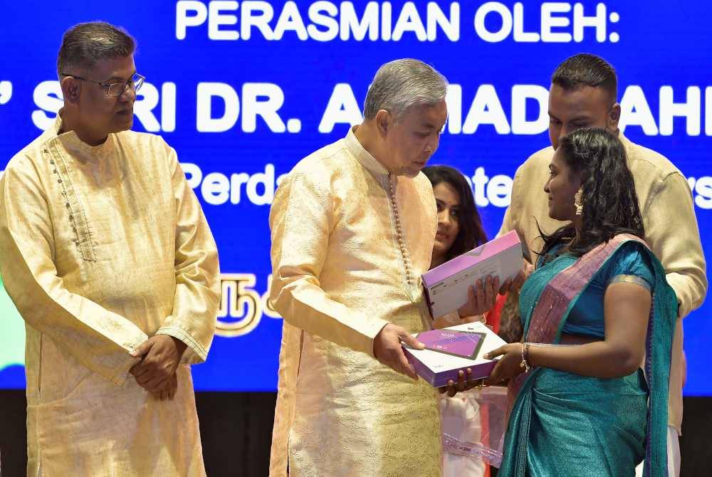 Ahmad Zahid (dua, kiri) menyampaikan bantuan tablet kepada 200 pelajar institut pengajian tinggi pada Majlis Sambutan Ponggal Perpaduan 2024 di Seksyen 16, Shah Alam pada Ahad. Foto Bernama
