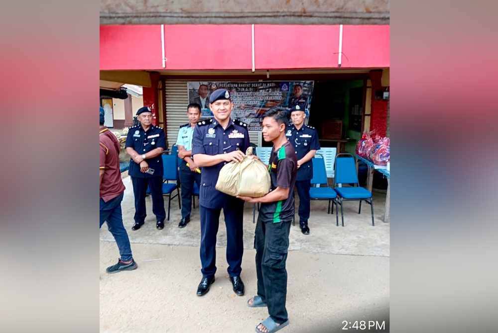 Mohamad Ismail (kiri) menyampaikan sumbangan makanan kepada keluarga nelayan.