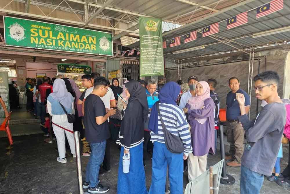 Orang ramai kelihatan berbaris sebelum mendapatkan makanan yang dijual di Nasi Kandar Sulaiman.