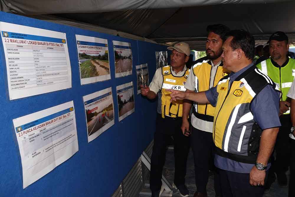 Alexander (kanan) melihat data-data dan gambar banjir di laluan FT003 Johor Bahru-Mersing. Foto Bernama
