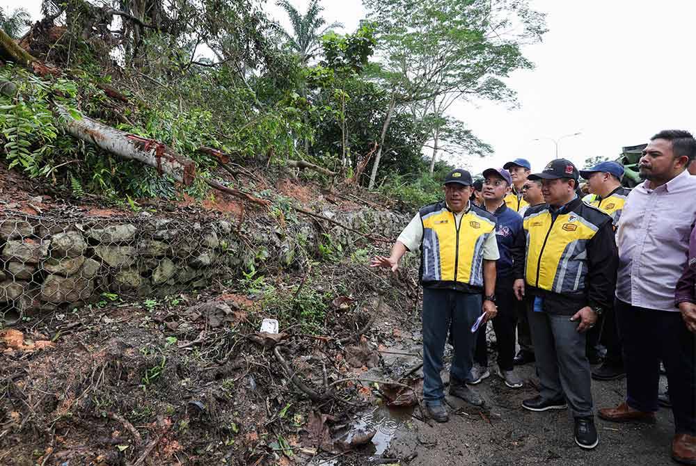 Alexander (depan, tengah) melihat dari dekat cerun bukit yang terjejas akibat banjir di laluan Johor Bahru - Endau. Foto Bernama