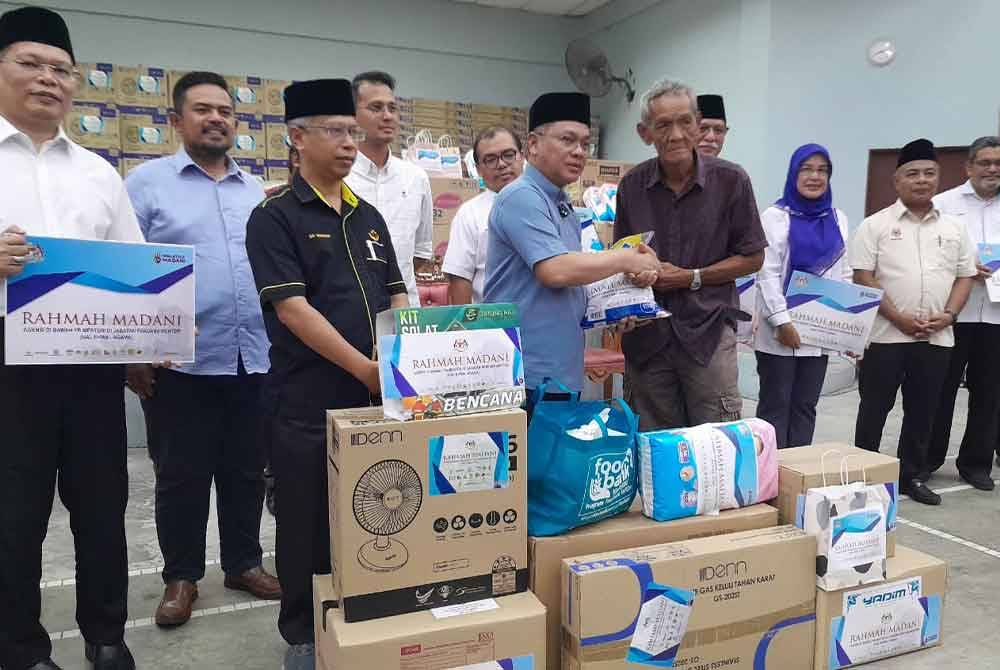 Mohd Na'im menyampaikan bantuan kepada penerima dalam program Misi Bantuan Pasca Banjir Agensi di Bawah Menteri di Jabatan Perdana Menteri (Hal Ehwal Agama) di Dewan Kampung Sungai Telor, Kota Tinggi pada Ahad