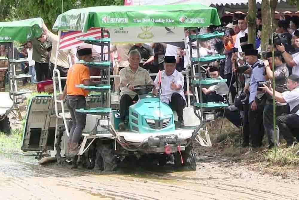 Al-Sultan Abdullah (kiri) dan Mohamad memandu jentanam di sawah padi di Kampung Merchong selepas merasmikan Program Smart Sawah Berskala Besar (Smart SBB) Ala Sekinchan di sini pada Isnin.