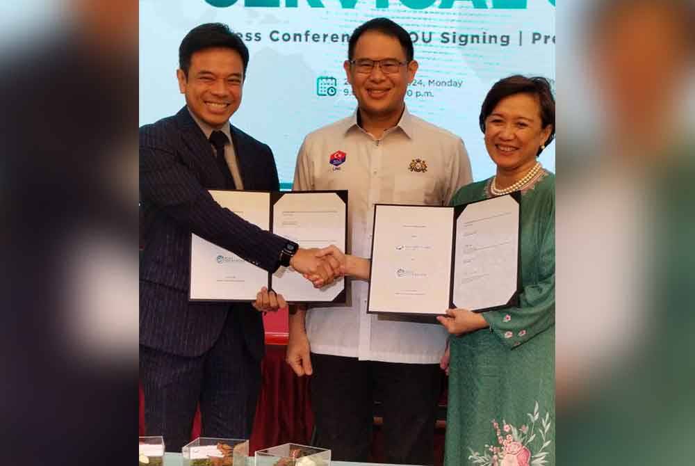 Tian Soon (tengah) menyaksikan pertukaran MOU antara Kamal dan Adeeba pada majlis di Johor Bahru.