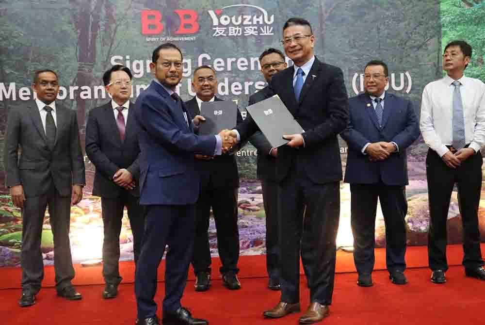 Raja Shahreen Raja Othman (berdiri depan, kiri) dan Presiden Shanghai Youzhu Industry Co. Ltd, Yu Qiang ( berdiri depan, kanan) bersalaman serta bertukar buku MoU sambil disaksikan Menteri Besar Kedah, Datuk Seri Muhammad Sanusi Md Nor ( berdiri belakang, tiga dari kiri).