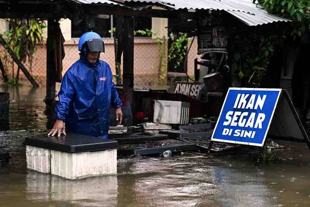 Seorang peniaga mengeluarkan kotak yang berisi ikan selepas gerainya dinaiki air berikutan hujan lebat sejak malam tadi ketika tinjauan Bernama di Jalan Kamaruddin pada Selasa.Foto Bernama