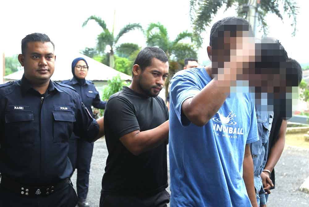 Mohd Ruzainis (berbaju hitam) diiring polis ketika hadir ke mahkamah.